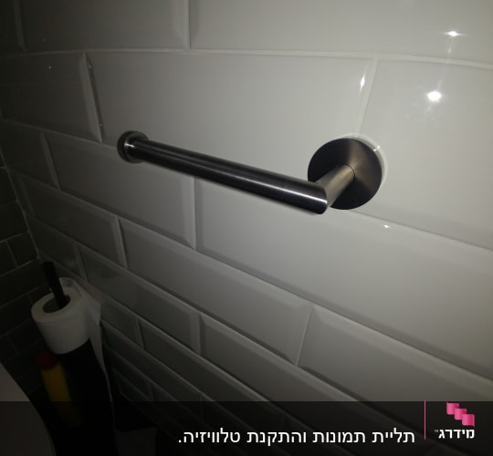 מוט מתכת מותקן על קיר אריחים לבנים